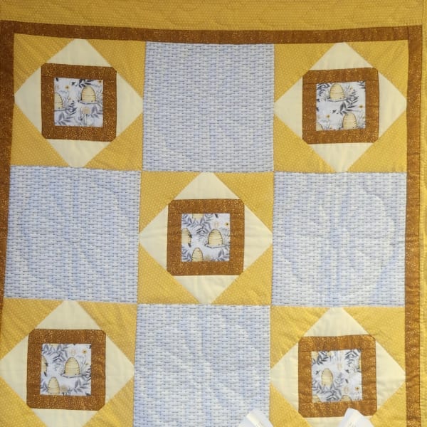 Yellow and white patchwork quilt with bee-patterned squares
