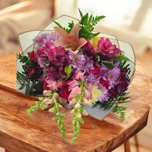 Mixed bouquet of pink, purple, and yellow flowers with a peach lily