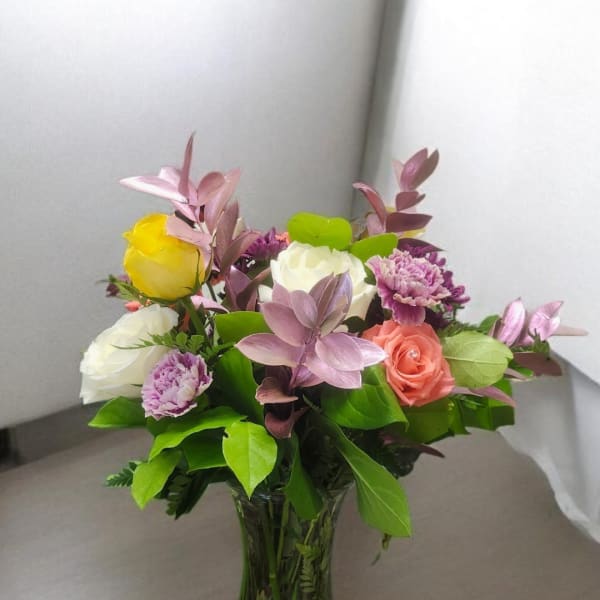Mixed bouquet of roses and carnations in a clear glass vase