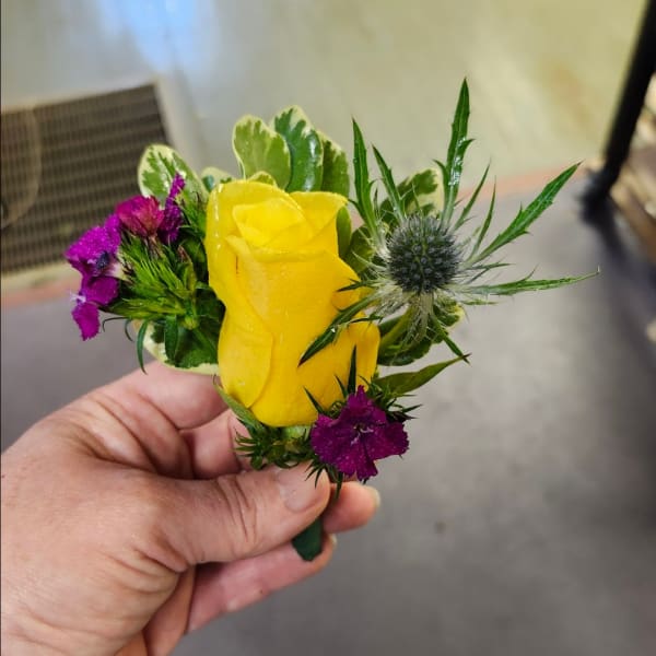 Yellow rose boutonniere with purple accent flowers and thistle