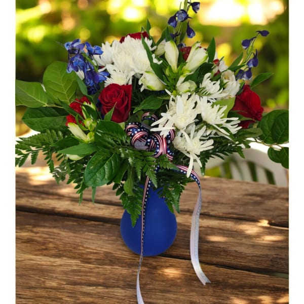 Red roses and white daisies in a blue vase with ribbon