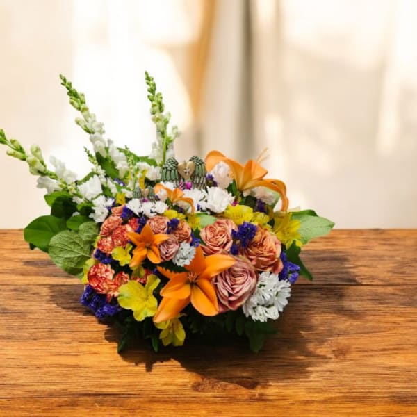 Mixed bouquet with orange lilies, peach roses, and white blooms on a wooden table