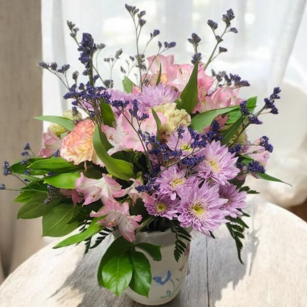 Pink and lavender mixed flowers arranged in a white vase