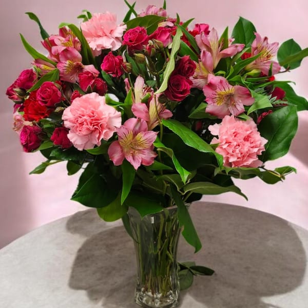 Pink roses and carnations in a clear glass vase