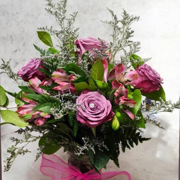 Pink roses and alstroemeria in a glass vase with pink ribbon