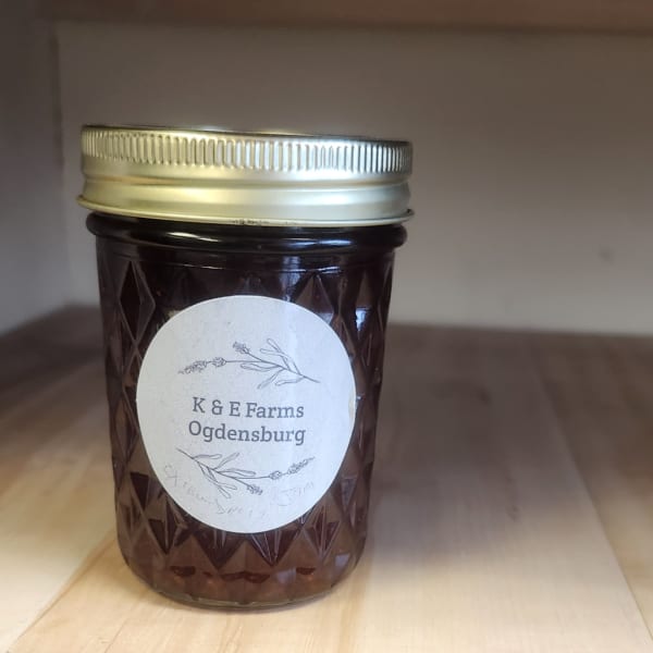 Dark glass jar with a silver lid and a K & E Farms Ogdensburg label