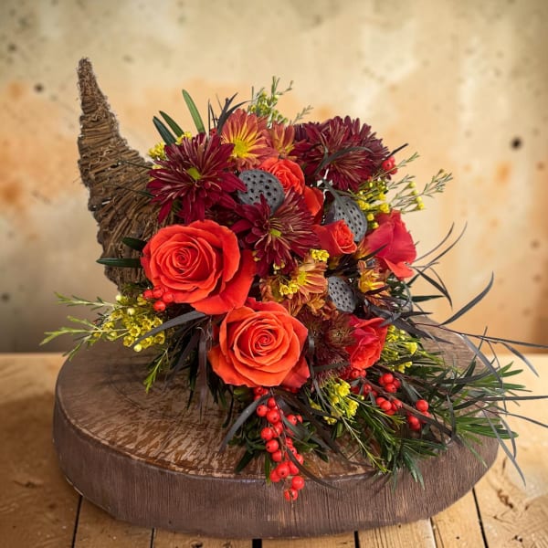 Orange roses and burgundy mums arranged in a rustic basket.