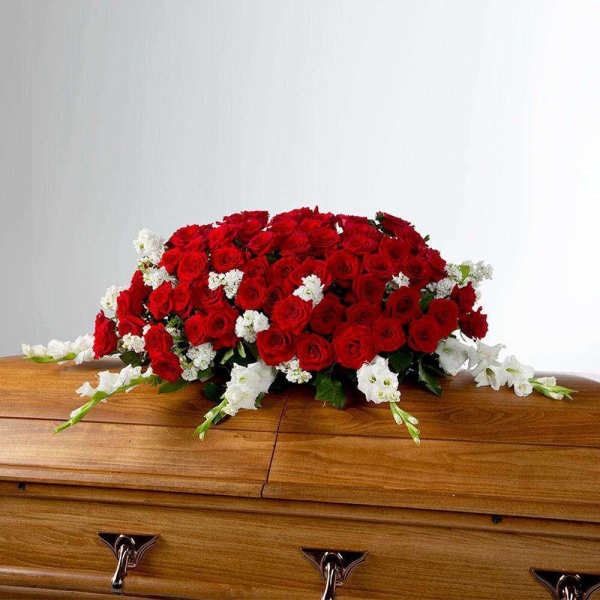 Red and white floral spray on a wooden casket