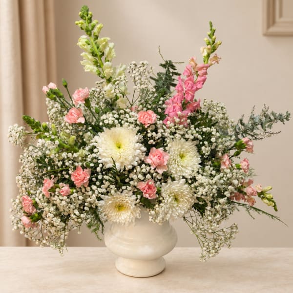 White and pink floral arrangement in a cream vase
