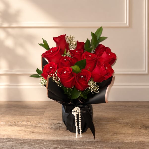 Bouquet of red roses wrapped in black paper with pearl accents