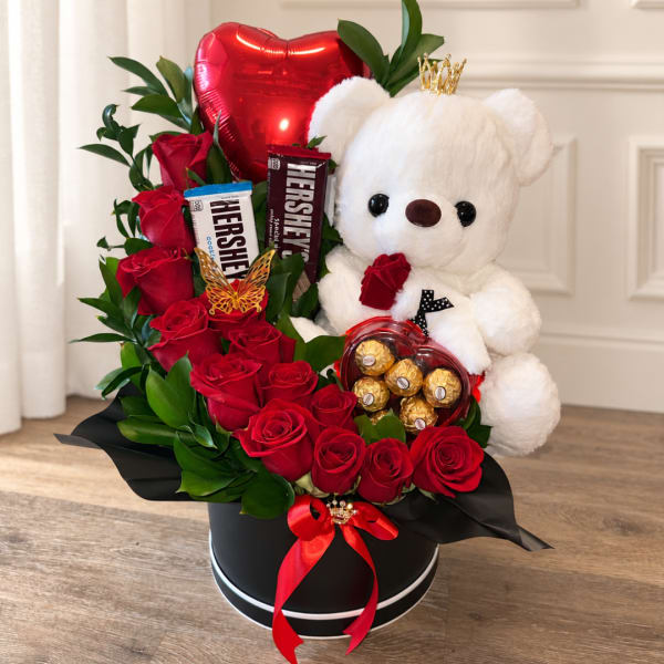 Red roses with a teddy bear, heart balloon, and chocolates in a black box