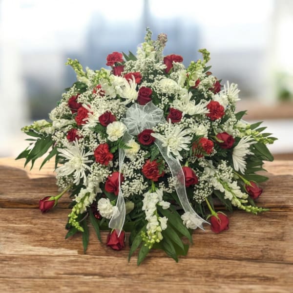 Red and white floral arrangement with ribbon on a wooden table
