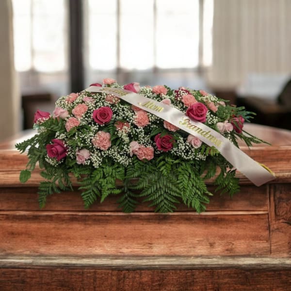 Pink and white floral casket spray with a satin ribbon
