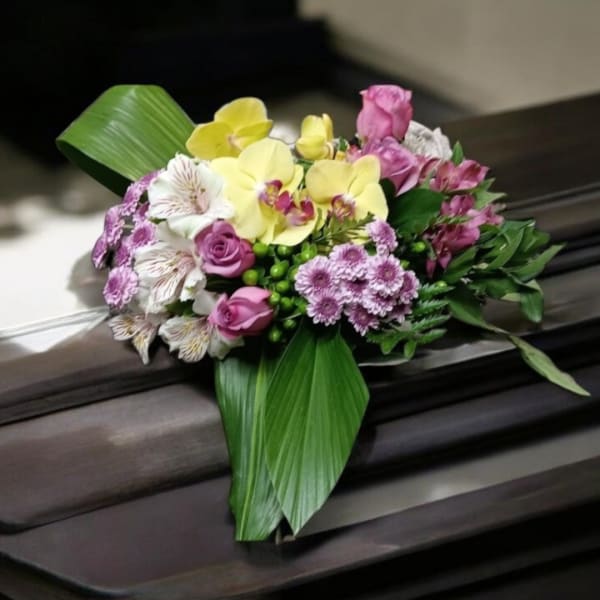 Pink and yellow floral arrangement with orchids and roses