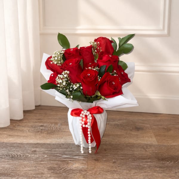 Bouquet of red roses in white wrapping with a red ribbon
