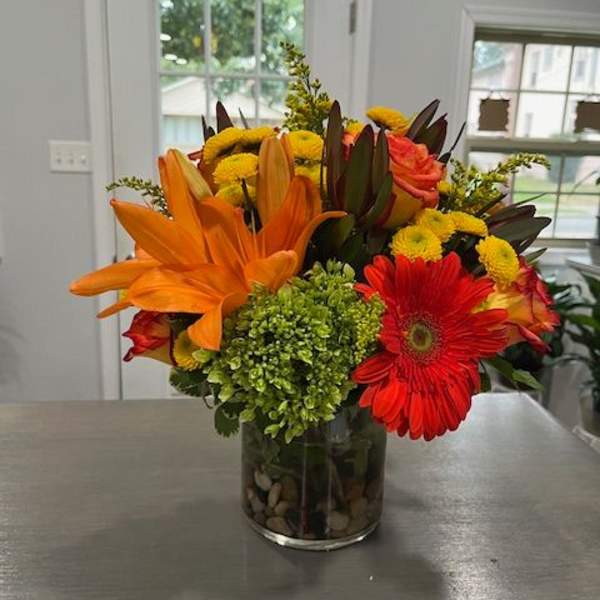 Bright mixed bouquet in a glass vase with orange lilies and red gerbera daisies