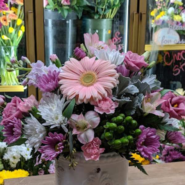 Pink and white mixed flower arrangement in a white ceramic container