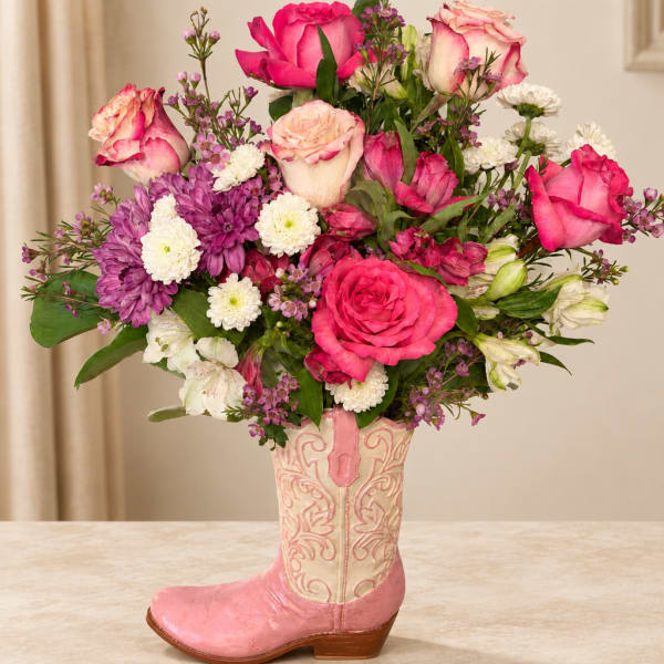 Pink and white flower arrangement in a pink cowboy boot vase