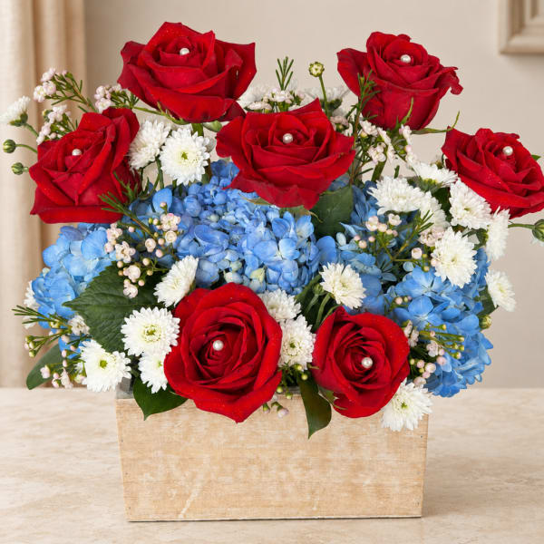 Red roses and blue hydrangeas in a square vase