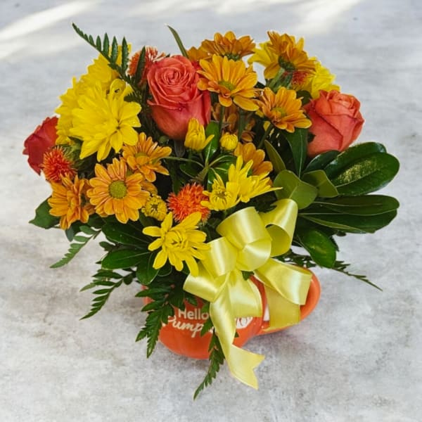 Orange and yellow flower bouquet in a pumpkin-shaped mug with a ribbon