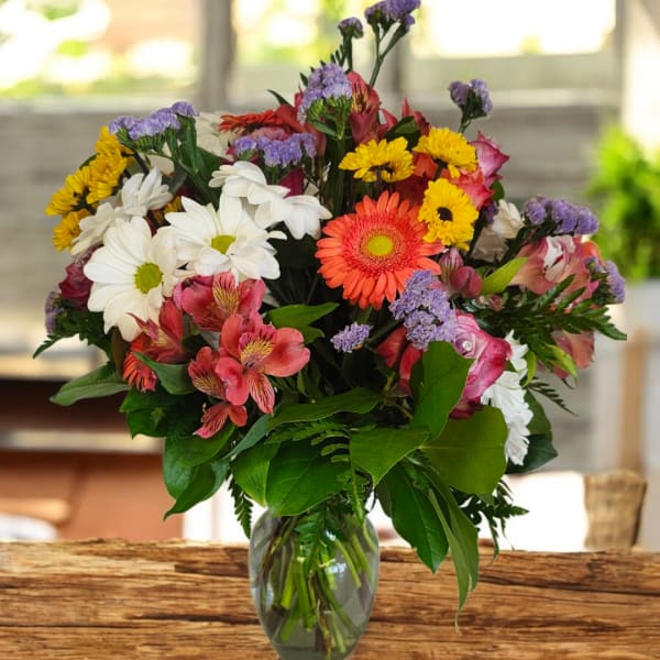Mixed bouquet of daisies, gerbera daisies, and alstroemeria in a glass vase