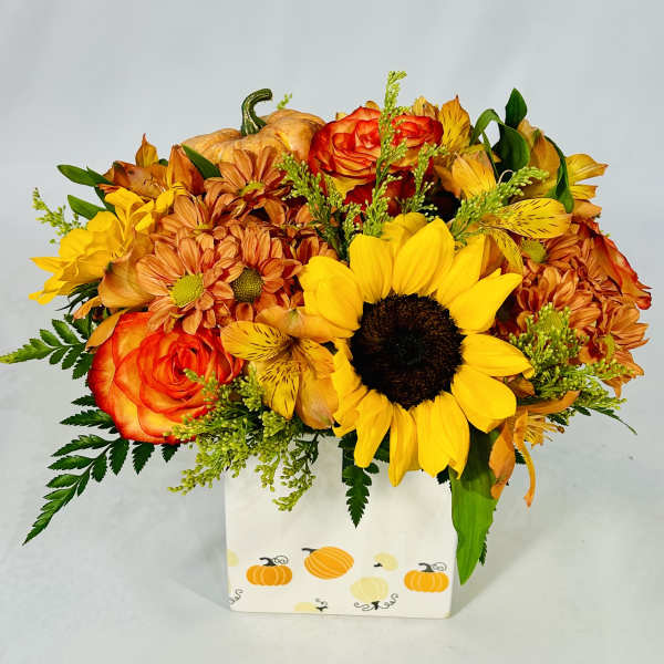 Autumn bouquet of sunflowers, roses, and mums in a pumpkin-decorated box
