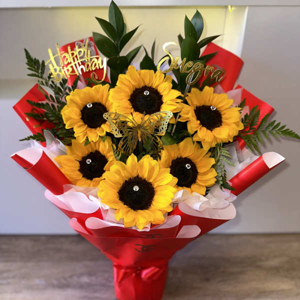 Sunflower bouquet in red wrapping with birthday toppers