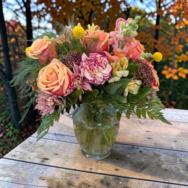 Mixed bouquet of pink and peach flowers in a clear glass vase