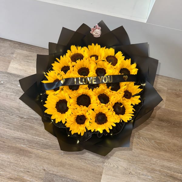 Bouquet of yellow sunflowers wrapped in black paper with a ribbon