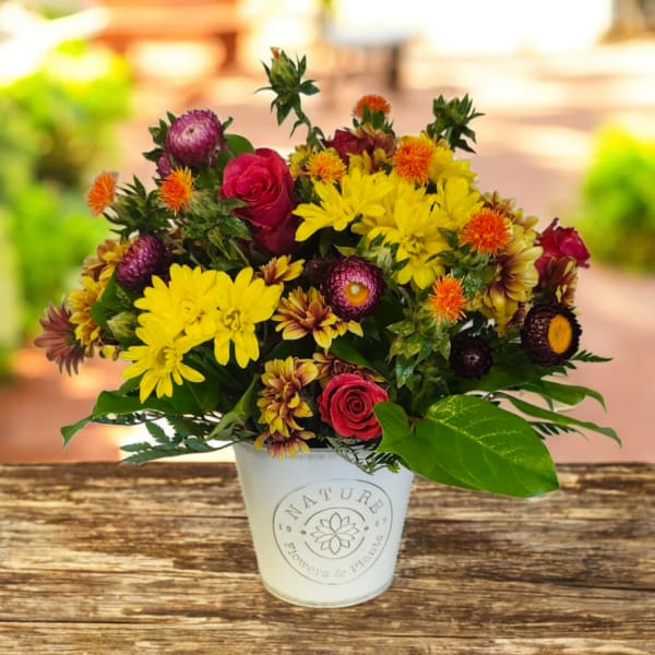 Mixed bouquet of yellow and red flowers in a white container