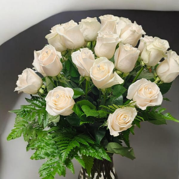 Cream rose bouquet with fern foliage in a clear vase