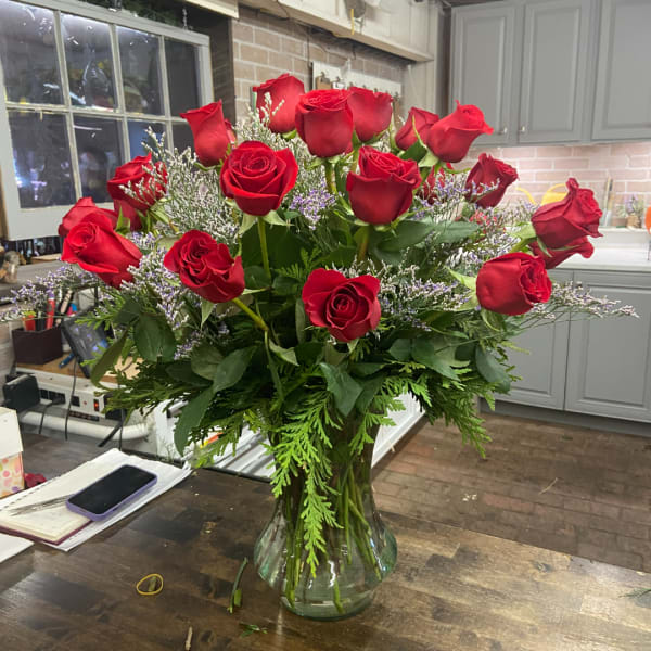 Red roses arranged in a clear glass vase with airy filler flowers