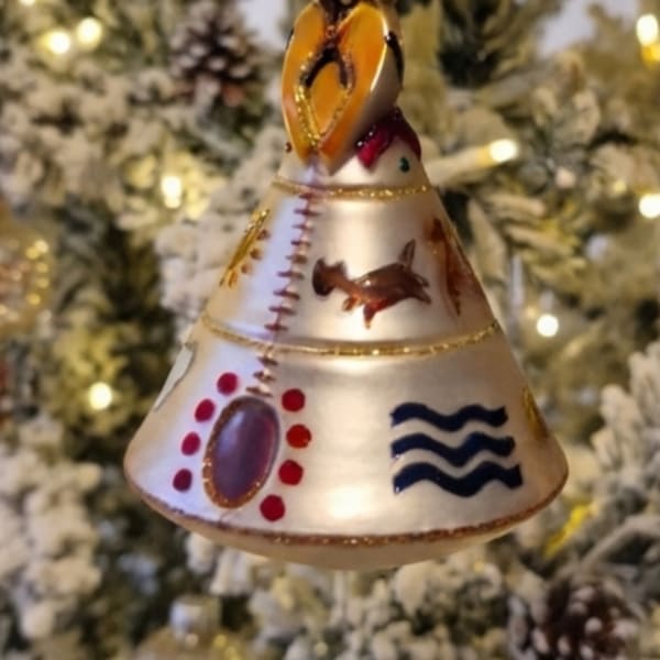 Decorative bell-shaped Christmas ornament hanging in front of a lit tree