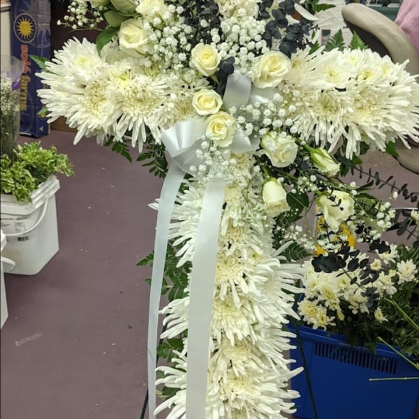 White floral cross with roses and ribbon on a stand