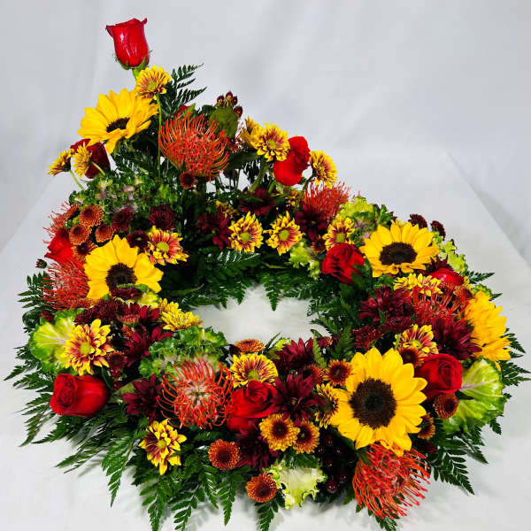 Circular floral wreath with sunflowers, red roses, and orange blooms