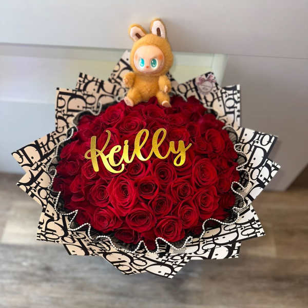 Red rose bouquet with a small plush toy and gold name topper