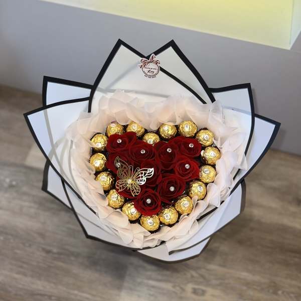 Heart-shaped bouquet of red roses and gold chocolates wrapped in white paper