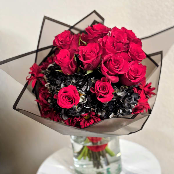 Bouquet of hot pink roses with dark filler flowers in a clear vase