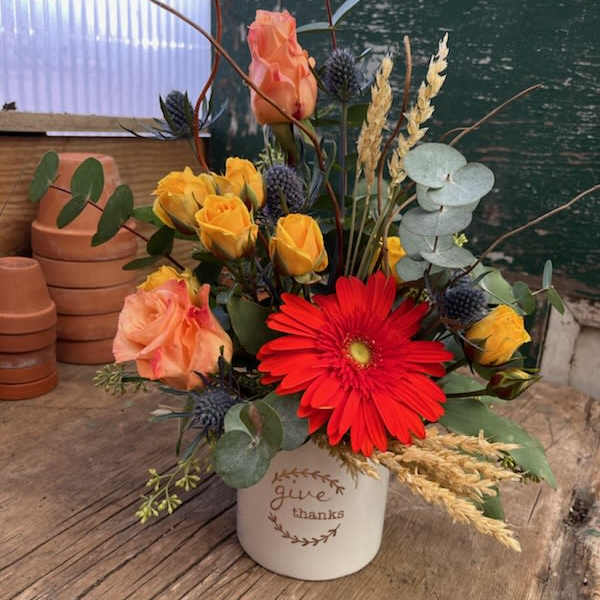 Mixed bouquet in a white bucket with red and peach flowers