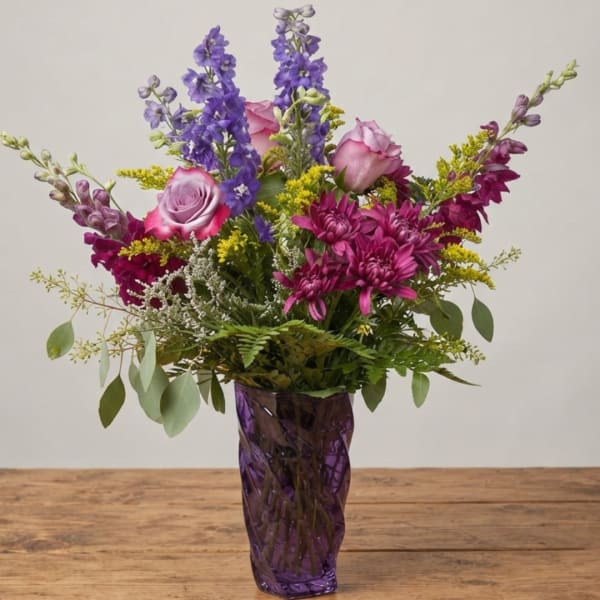 Purple and pink mixed bouquet in a purple glass vase