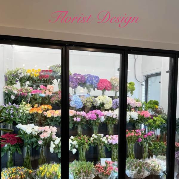Flower shop display case filled with colorful bouquets and vase arrangements