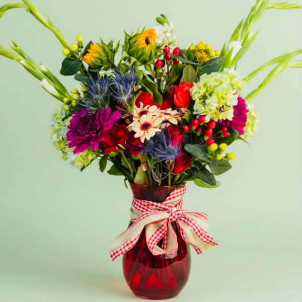 Colorful mixed bouquet in a red glass vase with a gingham ribbon
