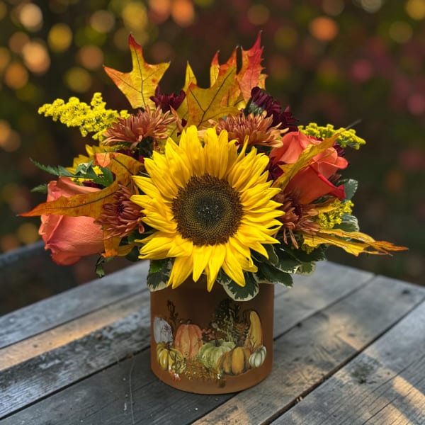 Sunflower and rose arrangement in a pumpkin-decorated container