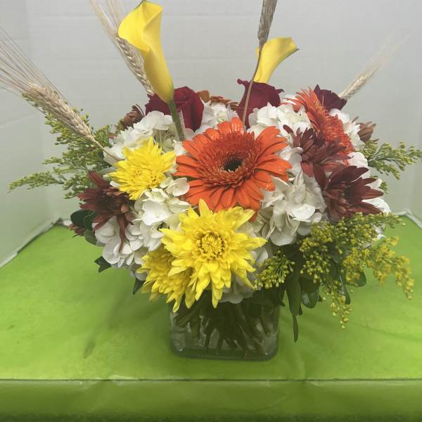 Mixed bouquet with calla lilies, gerbera daisies, and chrysanthemums in a glass vase