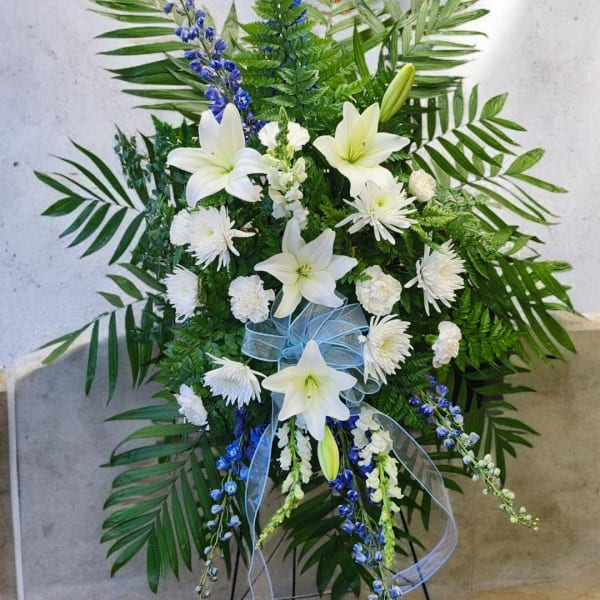 White lilies and chrysanthemums in a standing spray with blue ribbon