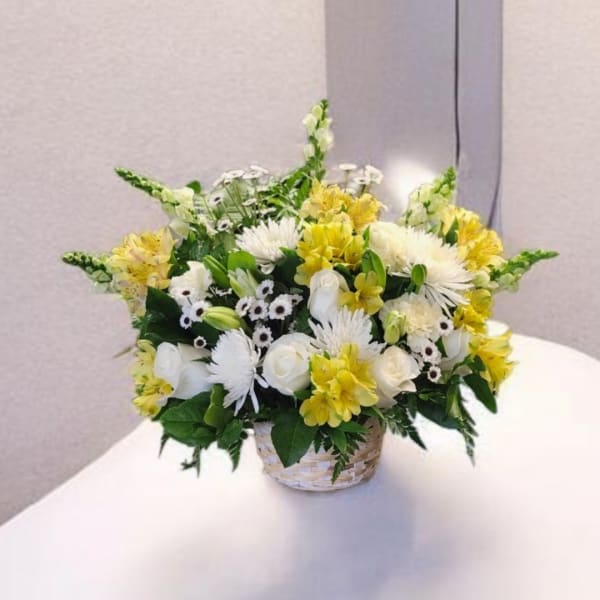 White and yellow mixed flower arrangement in a woven basket