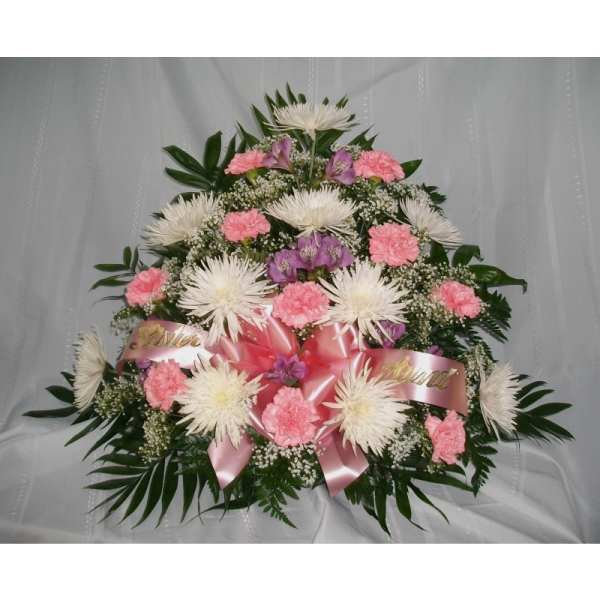 Pink and white floral spray with ribbon on a white draped background