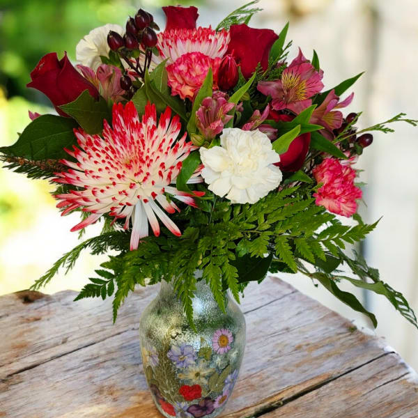 Bouquet of red, pink, and white flowers in a decorated glass vase
