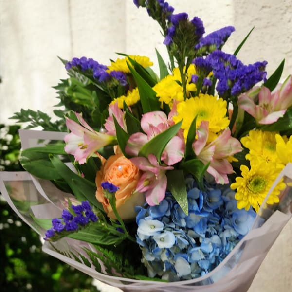 Mixed bouquet with blue hydrangea, yellow daisies, pink lilies, and purple filler flowers