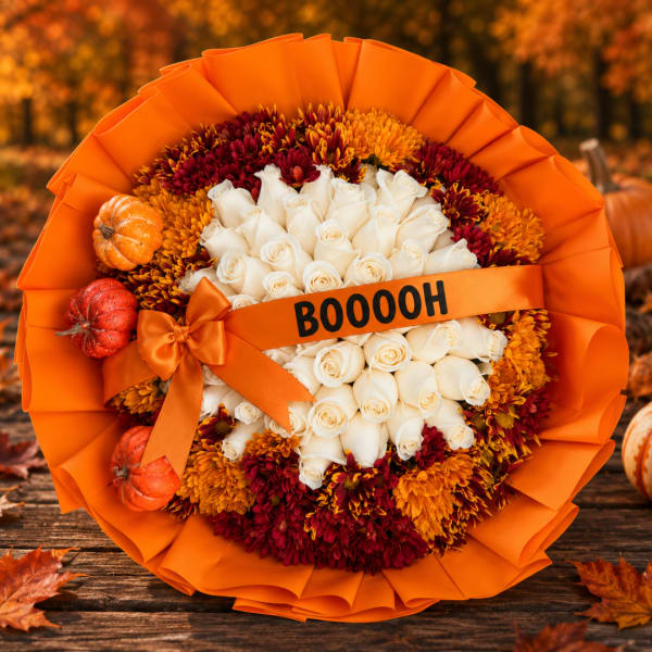 Orange-wrapped bouquet of white roses and autumn mums with small pumpkins